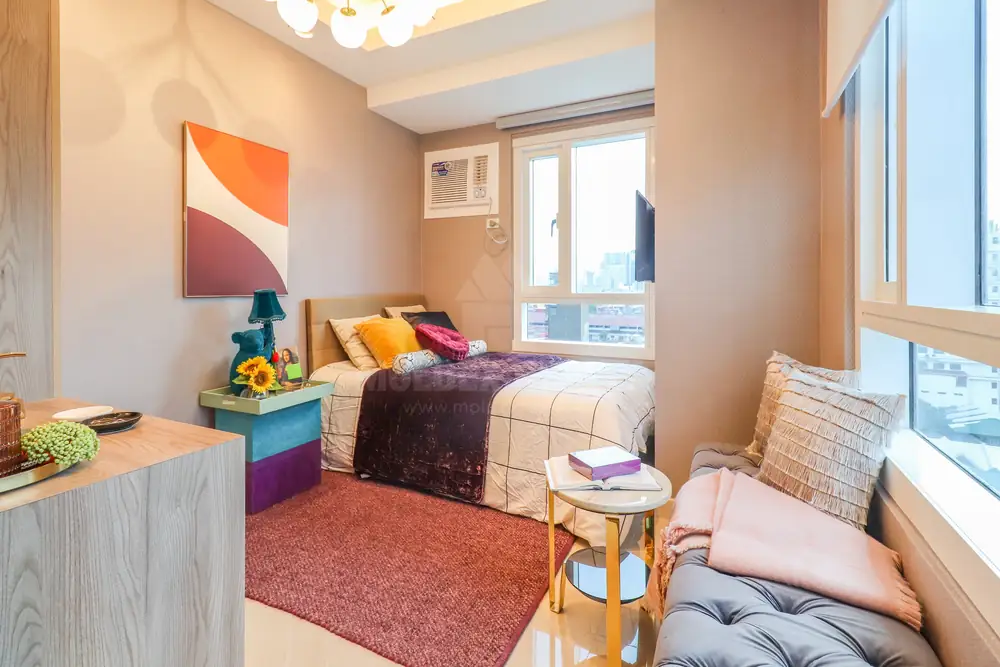 Bedroom of the 1BR model, where a cushioned window seat runs along the glass