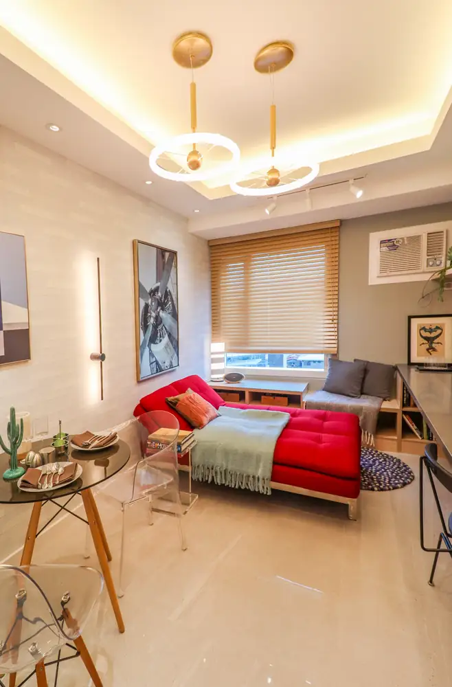 Looking toward the window, the studio's bed corner is styled with gold ring pendant lights